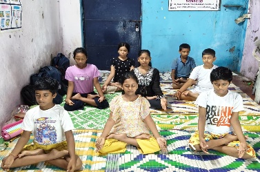 MKSS students sitting cross-legged in meditation during International Yoga Day